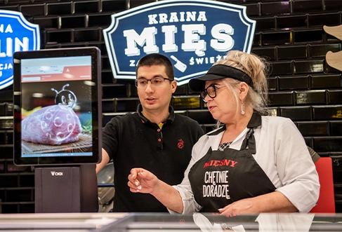 Two employees working on a meat counter with a weighing machine. (photo)