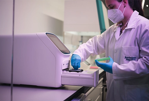 A woman in a lab coat working on samples with a Molecular Biology machine. (photo)