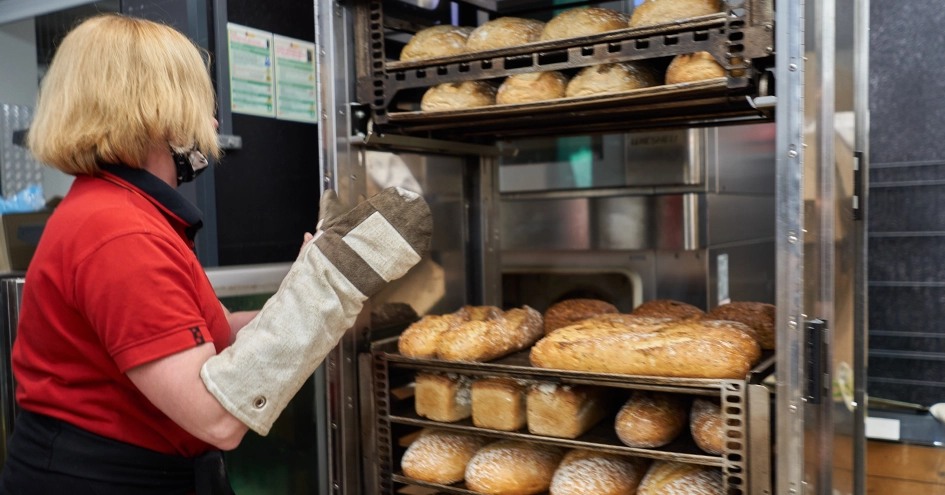 An employee moving a rack of freshly baked bread (photo)