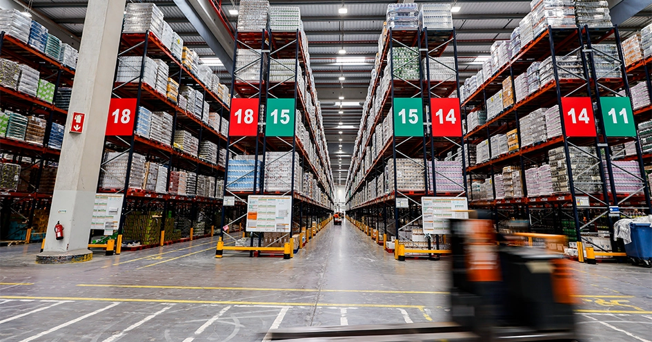 Shelves in a distribution centre with a forklift driving by in the front (photo)
