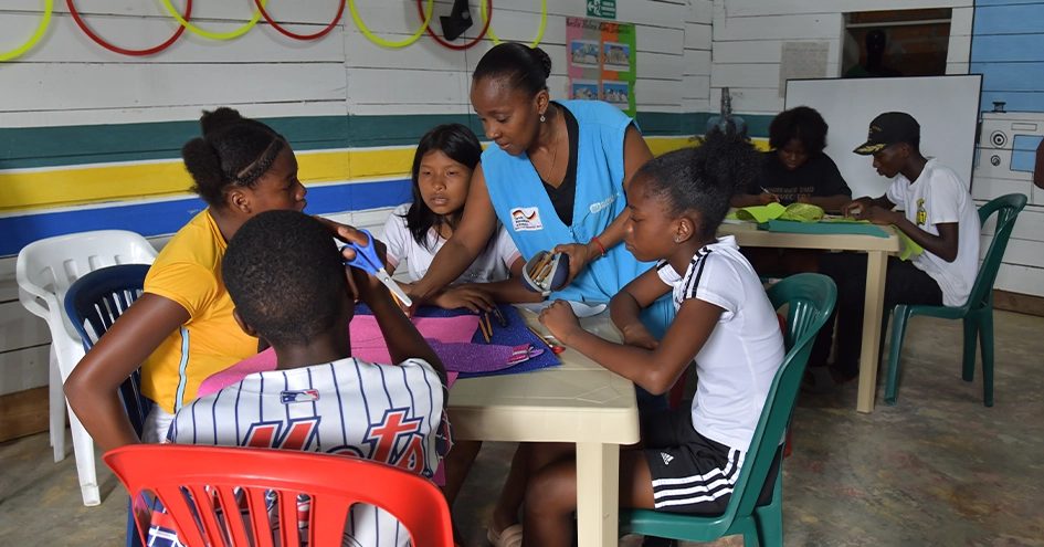 Children sitting arount two tables at the SOS Children’s Villages Colombia (photo)