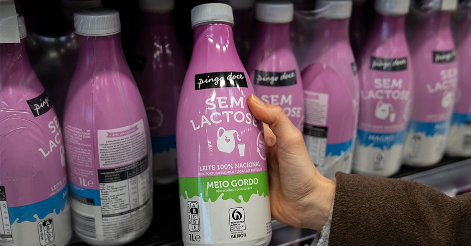 Close-up of a hand taking a lactose-free milk bottle from a shelf at Pingo Doce (photo)