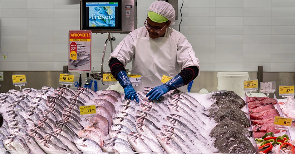 An employee at the fish counter arranging the fish on ice (photo)