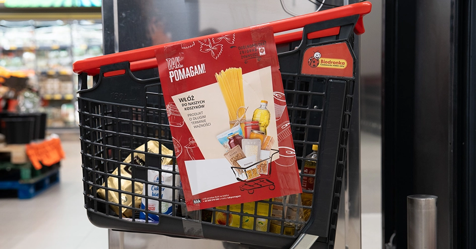 Um carrinho de compras da Biedronka com alguns produtos, fotografado de lado (foto)