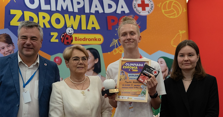 O vencedor da Olimpiada Zdrowia PCK a segurar o prémio com quatro pessoas à sua volta (foto)