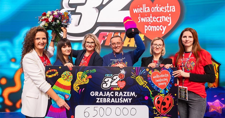 Vencedores da 32.ª final da Wielka Orkiestra Świątecznej Pomocy - WOŚP segurando flores e um cheque de 6500000zl (foto)