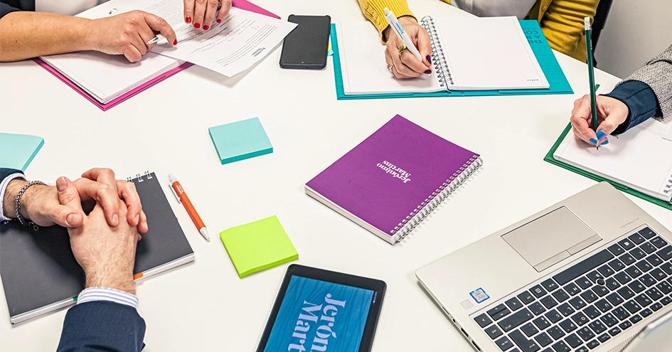 Vista de cima de uma reunião, mostrando apenas as mãos, os computadores portáteis, um tablet e um computador portátil (foto)