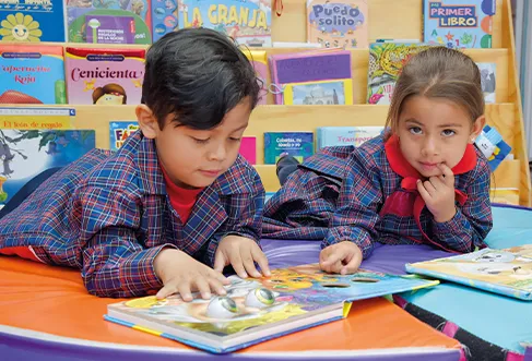 Um menino e uma menina a olhar e a apontar para imagens num livro infantil (foto)