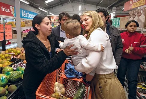 Uma mulher a entregar um bebé a outra mulher numa loja Ara cheia de clientes (foto)