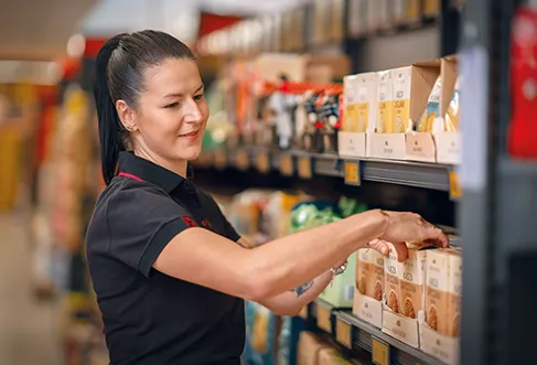 Um colaborador a organizar produtos num linear de supermercado (foto)