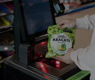 Uma pessoa a passar um pacote de abacates congelados no caixa de pagamento automático do Pingo Doce.
