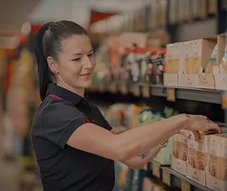 Colaborador a organizar produtos num linear de supermercado da Biedronka.