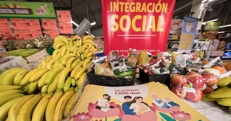 Secção de produtos hortícolas e frutas numa loja Ara, com diferentes frutas, como bananas e maçãs, bem como cartazes de promoções. (foto)