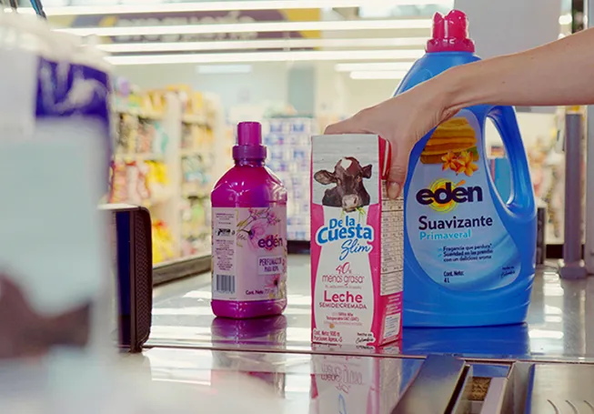 A mão de um colaborador a alcançar produtos de limpeza e leite para os passar na caixa registadora (foto)